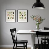 Black-framed botanical posters above table with vase.
