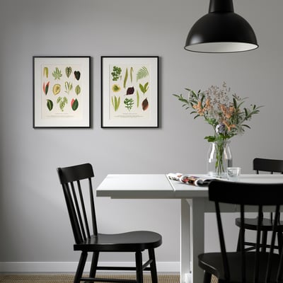 Black-framed botanical posters above table with vase.
