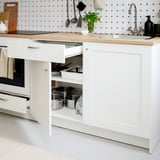 Modern kitchen with open drawer; neat pots and pans; wood worktop; tidy shelter.