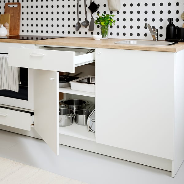 Modern kitchen with white cabinets, oak countertop, stainless steel pots, and a backsplash with black polka dots.
