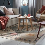 Cozy living room with KNYLHAVRE rug, beige & multicolored, wool & cotton, 5x8 feet, under coffee table, sofa, and wicker chair.