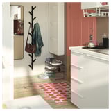 Modern entryway with a red polka dot mat, shoe rack, and black coat rack holding jacket and purse.