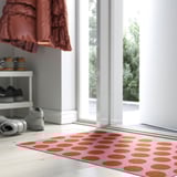 KÖRFÄLTSPIL mat, red with white dots, lies near a shoe rack and a door, smaller than the shoe rack, rubber-backed, circular patterns.