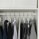 Closet with KOMPLEMENT rail, hanging clothes neatly. Includes black, gray, and dotted shirts on hangers.