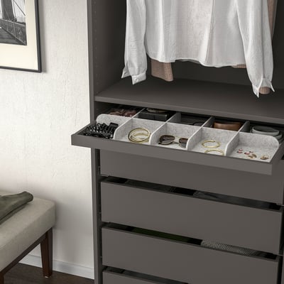 Organized grey drawer unit pulls out for easy access, showing compartments holding jewelry, watches, and small accessories.