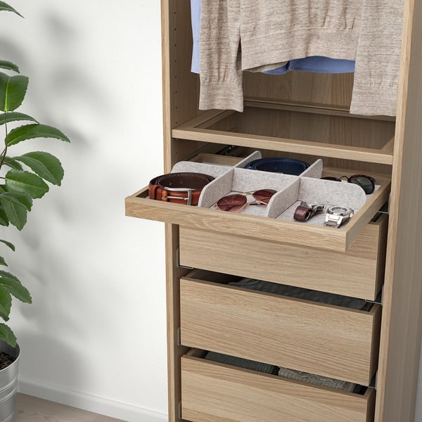 Open wooden drawer with felt dividers holding belts and accessories.