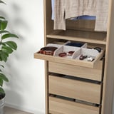 Open wooden drawer with felt dividers holding belts and accessories.