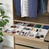 Organized drawer with multiple compartments for accessories like belts, ties, and watches in a wooden closet, featuring a slow-closing mechanism.