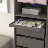 Gray wardrobes pull-out tray displays jewelry, including necklaces, bracelets, and a watch, showcasing effective organization and easy access.