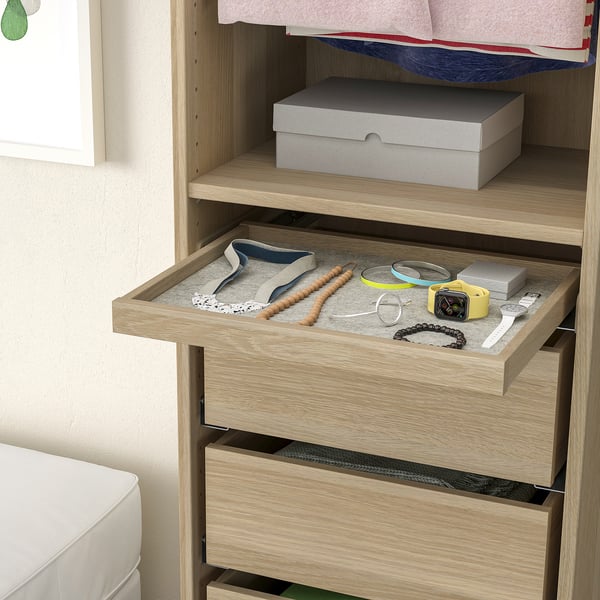 Wooden dresser with open drawer showing jewelry organizer. Drawer contains trays with watch, bracelets, and necklaces.
