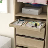 Wooden dresser with open drawer showing jewelry organizer. Drawer contains trays with watch, bracelets, and necklaces.
