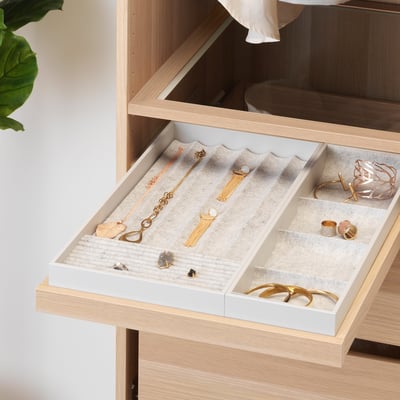 Open wooden drawer with jewelry tray displaying necklaces, rings, and earrings.
