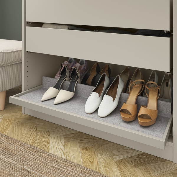Pull-out shoe tray in wardrobe with felt lining for shoe organization.