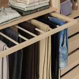 Organized pants hanger in wardrobe, displaying several pairs neatly.