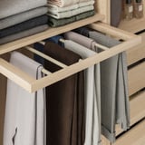 Wooden trouser organizer with 6 arms, holding 12 pairs of pants, neatly arranged in an open drawer.