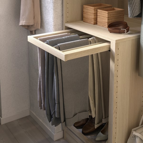 KOMPLEMENT trouser hanger holds grey pants in light wood shelf.