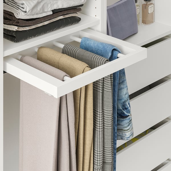 A white wardrobe drawer with a trouser hanger holding four pairs of neatly folded pants.
