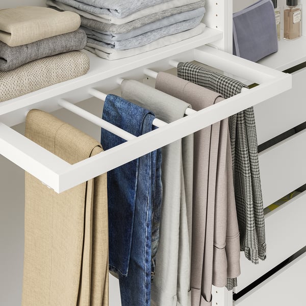 Closet with pull-out trouser hanger holding several pairs of jeans and trousers.