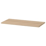 A flat light brown wooden shelf named KOMPLEMENT. Its rectangular with smooth edges and a simple design.