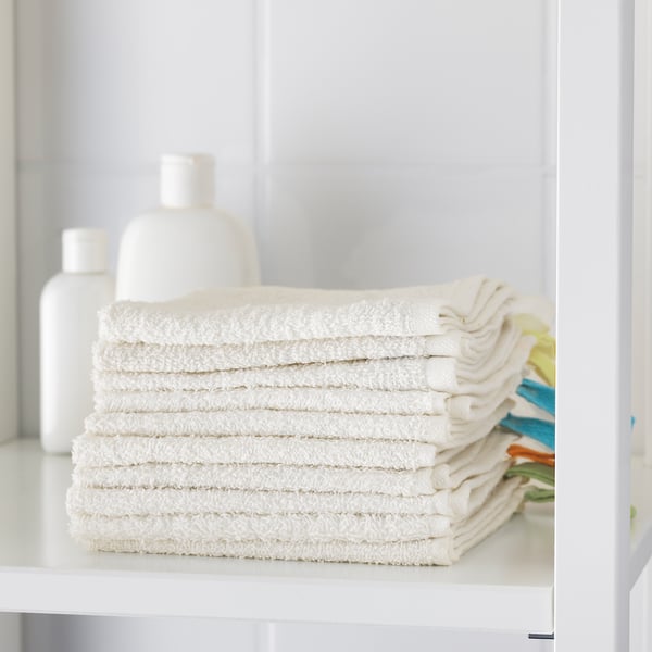 A shelf with neatly stacked white cotton towels, perfect for cleaning hands, purifying skin, and changing diapers.