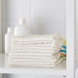 A shelf with neatly stacked white cotton towels, perfect for cleaning hands, purifying skin, and changing diapers.