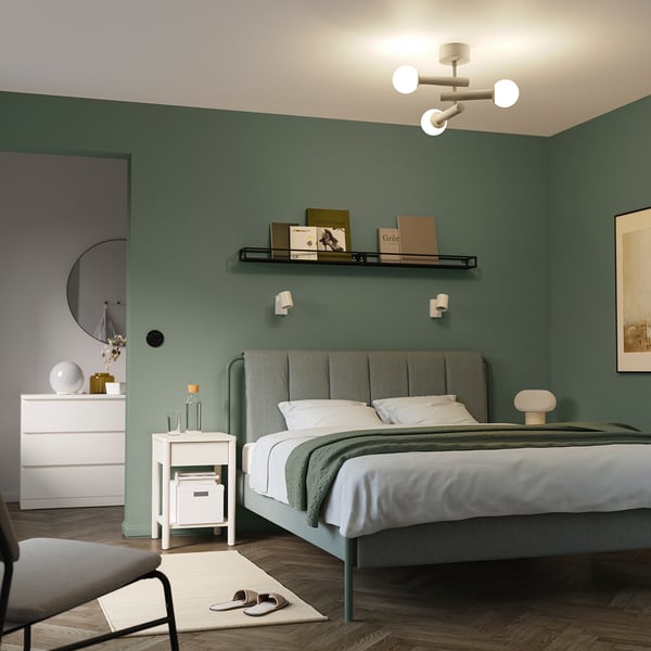 Modern bedroom with green walls, white ceiling lamp, and white furniture.