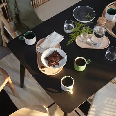 Table setting with chocolate, cups, and blanket.
