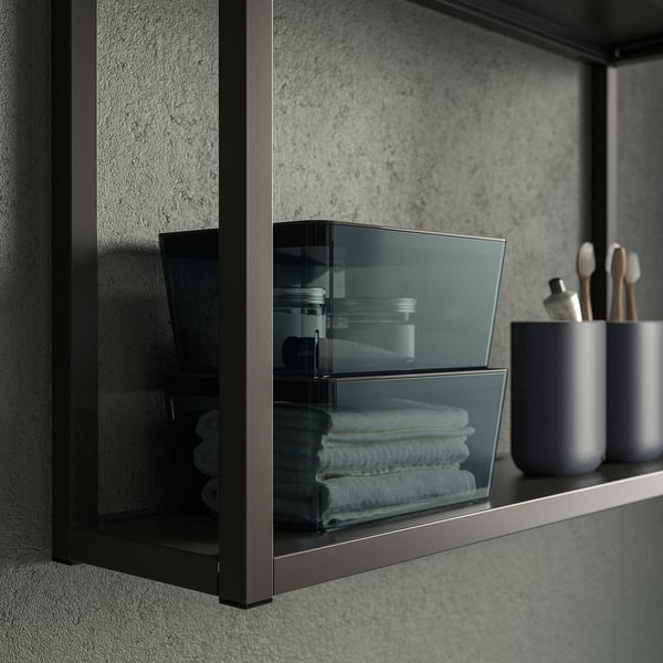 Small stackable storage box, ideal for organizing small items like cables or toiletries. Shown with folded towels in a bathroom setting.