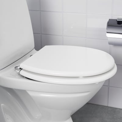 White toilet with closed lid, integrated slow-close hinge, tiled wall backdrop.