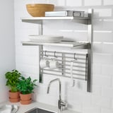 Wall-mounted kitchen storage rack with adjustable shelves holding plates and cups, featuring hooks for towels.