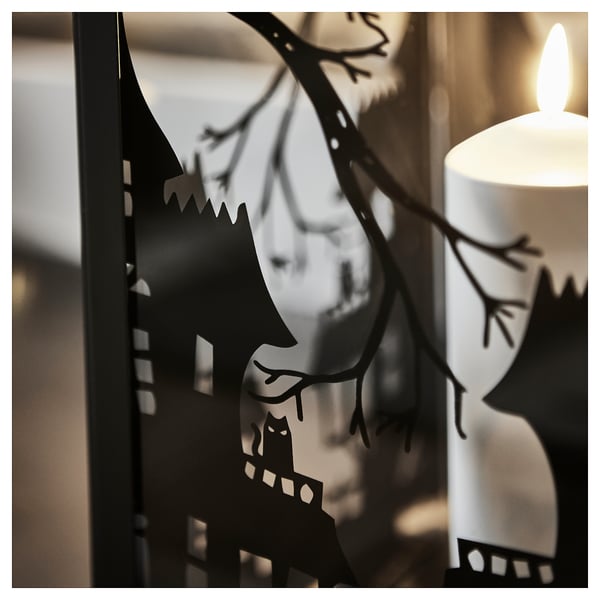 Decorative halloween lantern with spooky silhouettes, lit candle inside, casting eerie shadows.