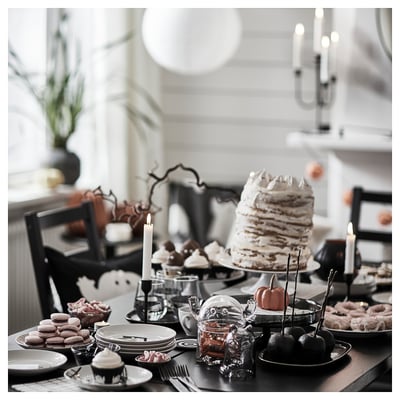 KUSTFYR black plates with spooky halloween decors, tiered cake with candles, desserts, and black chairs.