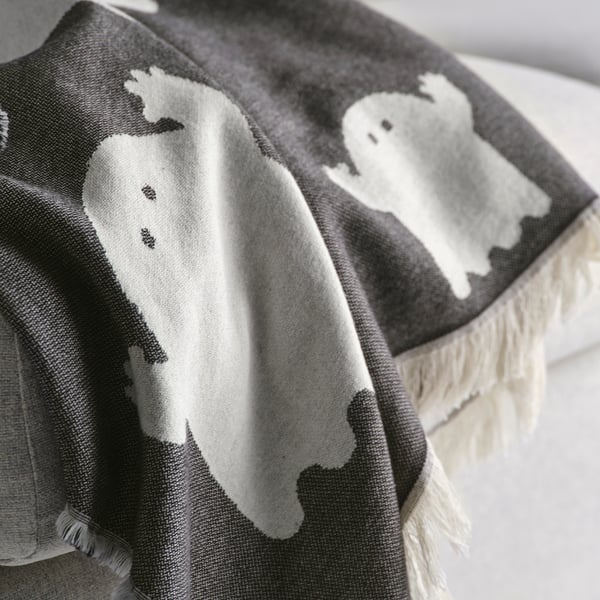Ghostly throw blanket, black and white, draped over edge, soft texture, cotton material.