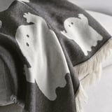Ghostly throw blanket, black and white, draped over edge, soft texture, cotton material.