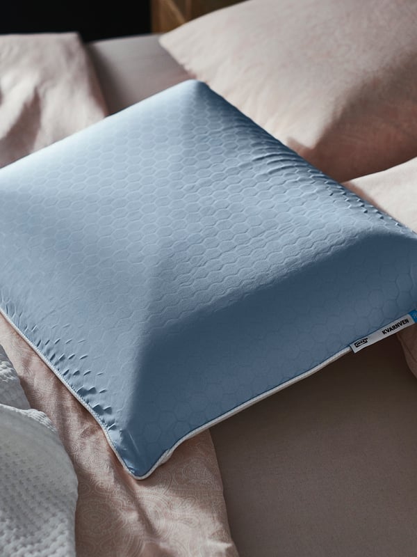 Blue ergonomic pillow with honeycomb pattern rests on a bed, showcasing its cooling side.