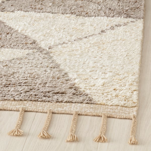 Handcrafted rug with intricate, dune-like patterns and fringe borders, displaying high-quality craftsmanship.