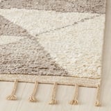 Handcrafted rug with intricate, dune-like patterns and fringe borders, displaying high-quality craftsmanship.