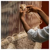 Person weaving rug, hands skillfully handling yarn.