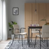 Modern dining area with grey LÄKTARE chairs, wooden cabinet, table, plant, and rug.