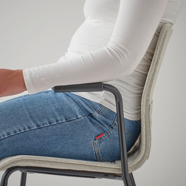 Person sitting in an office chair, showing armrests and fabric cover.