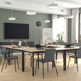 Modern green conference room with large screen, wooden tables, and LÄKTARE chairs. Pendant lights, clock, and windows with blinds.