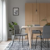 Modern dining set with wooden cabinet, table, grey LÄKTARE chairs, bulb light, plant, and patterned rug.