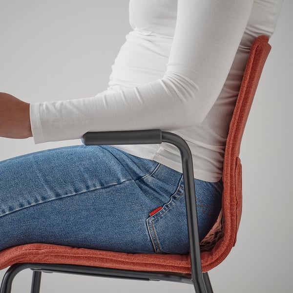 Person sits in LÄKTARE chair, showing lumbar support and armrests.