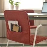 Red conference chair with pockets holding notepad and pen, designed for easy cleaning and organizing.