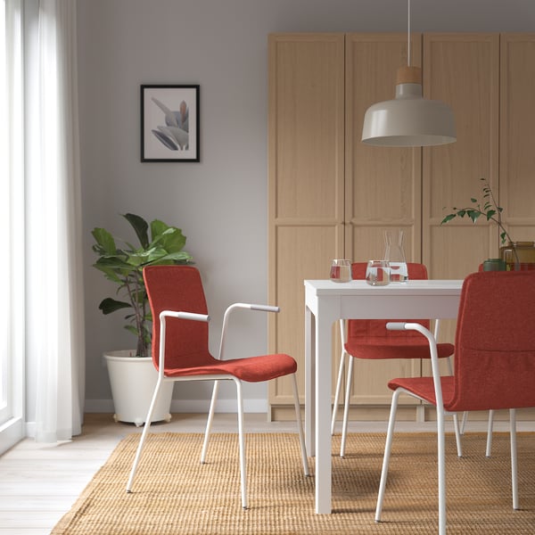 Modern dining area with red LÄKTARE chair and white frame. Wavy back and armrests, near table and cabinet, with a plant.