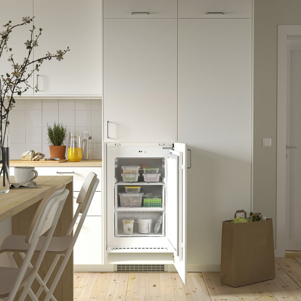 Kitchen scene: open fridge-freezer with clear drawers inside, placed under cabinet.