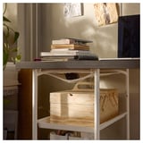 A LAGKAPTEN desk with a grey top and white legs, holding books, a laptop, and storage boxes.