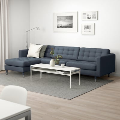 Modern living room with blue l-shaped sofa, white coffee table, rug, floor lamp, and wall art.