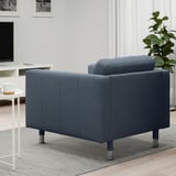 A cozy, modern armchair in a living room with a sleek, upholstered design and metal legs, positioned near a small table with a coffee cup.