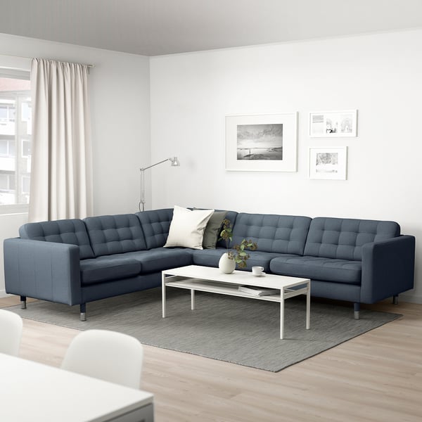 Modern living room with a blue l-shaped sofa, white coffee table, and floor lamp.